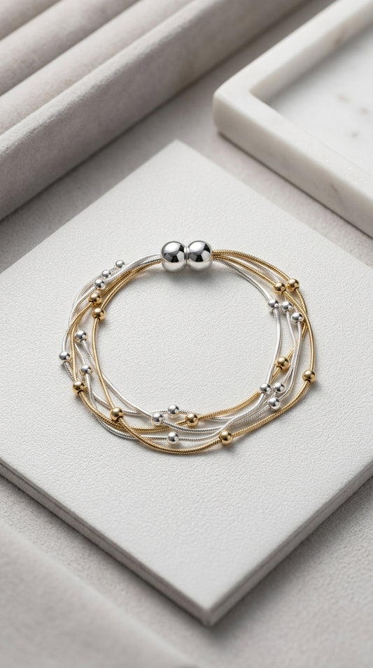 Gold and silver bracelet on a light gray surface with magnetic closure