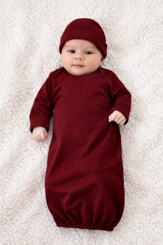 Baby wrapped in a red swaddle and hat on a light background