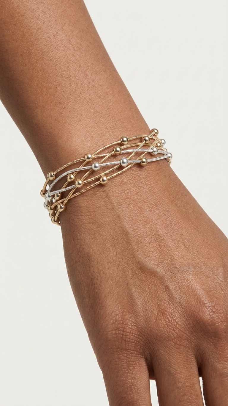 Gold bracelet with magnetic closure on a wrist against a light background