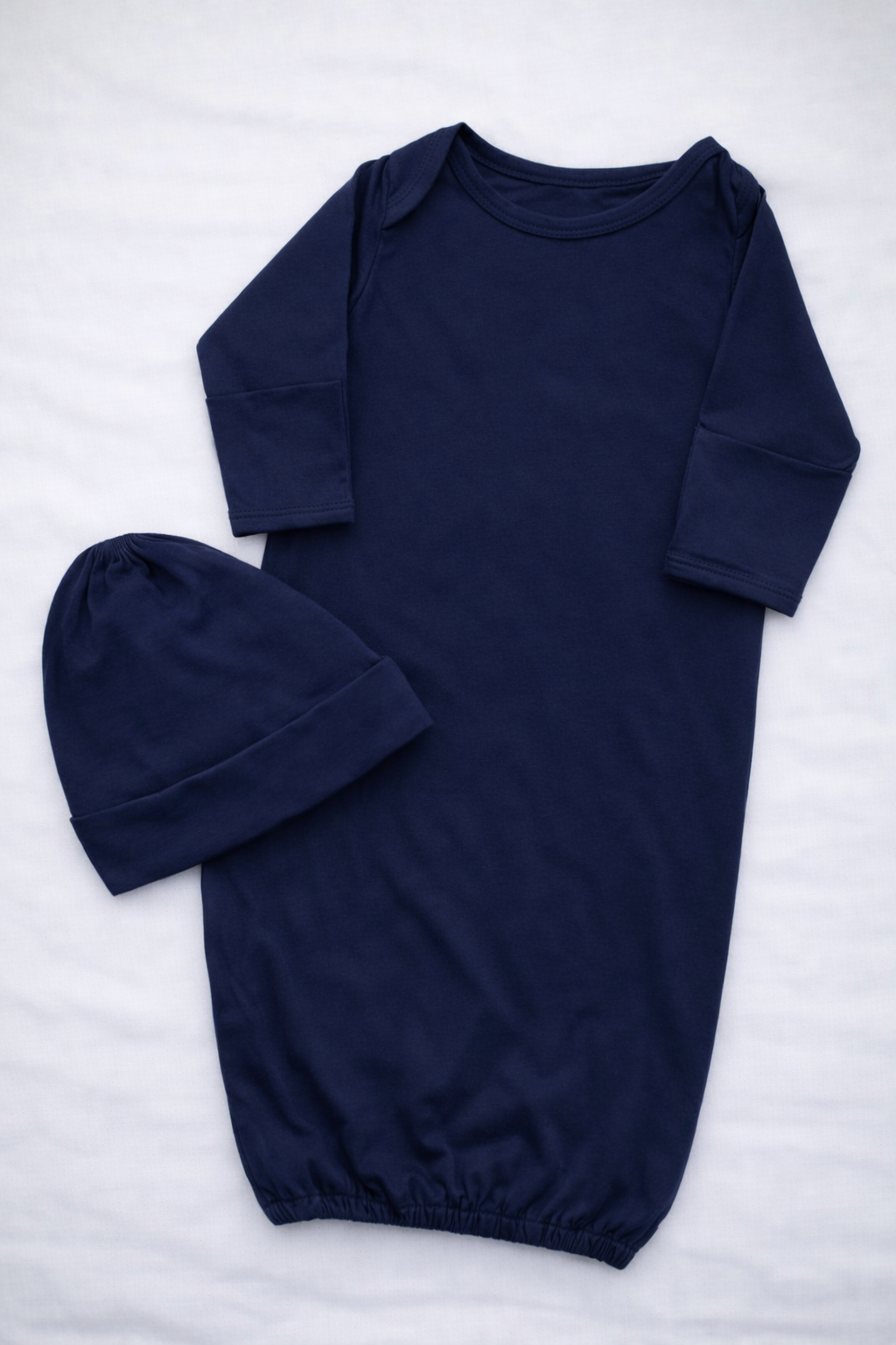 Navy blue baby gown and hat set on a white background