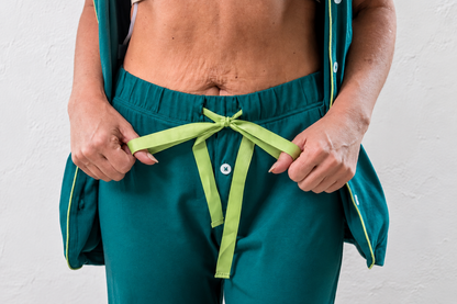 A close-up of a person wearing teal-green medical pajamas showing the adjustable waist.