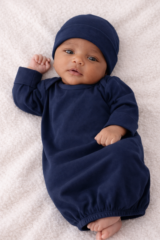 Baby wearing a navy blue outfit and hat on a white blanket